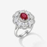 ruby oval halo ring — A deep red oval stone, framed twice over by ovals of white light